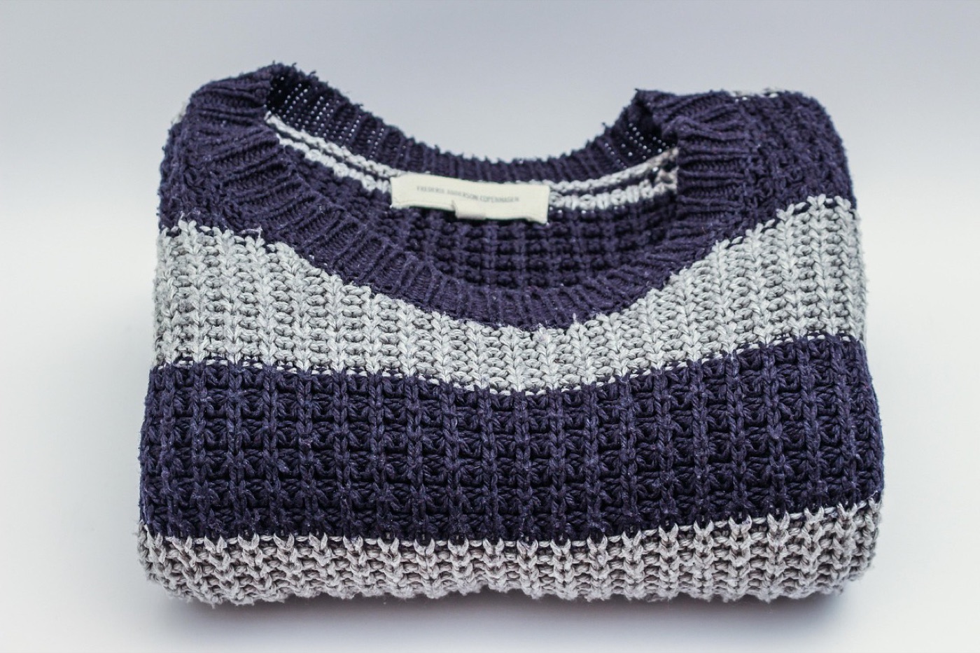 A folded knit sweater beside a printed product tag