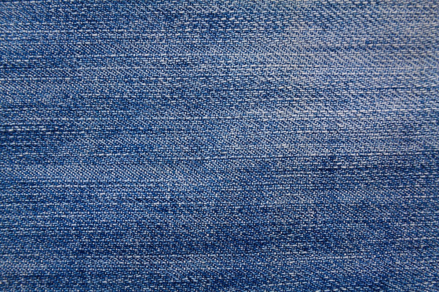 Close-up of dark indigo raw denim fabric with a copper rivet